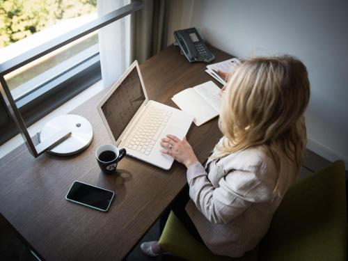 a woman sitting at a table with a laptop at Atlantic Congress Hotel Essen in Essen
