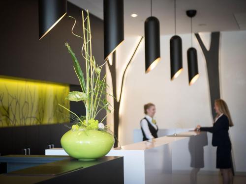a man and woman standing in an office with a green vase at Atlantic Congress Hotel Essen in Essen