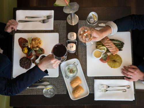 two people drinking wine at a table with food at Atlantic Congress Hotel Essen in Essen