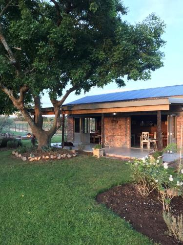 a brick house with a tree in the yard at Gerald's Gift Guest House in Addo