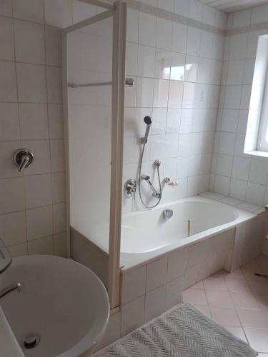 ein weißes Badezimmer mit Badewanne und Waschbecken in der Unterkunft Beim Dobis in Lutzingen