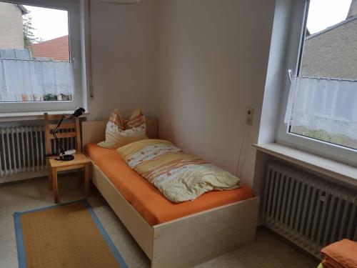 ein kleines Bett in einem Zimmer mit zwei Fenstern in der Unterkunft Beim Dobis in Lutzingen