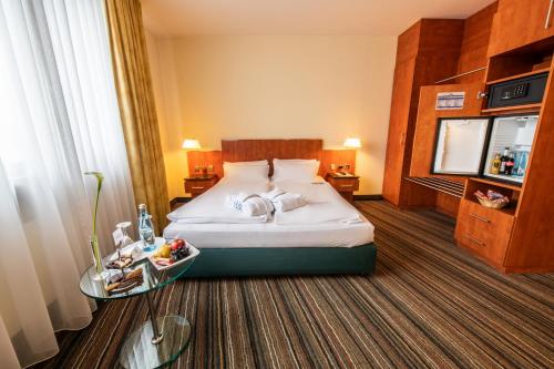 a hotel room with a bed and a table at Mercure Hotel am Messeplatz Offenburg in Offenburg