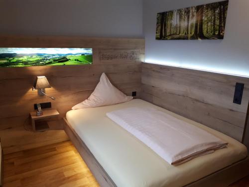 a bedroom with a white bed with a tv on the wall at Hotel Bigger Hof - Wirtshaus Platzhirsch am Jahnplatz in Olsberg