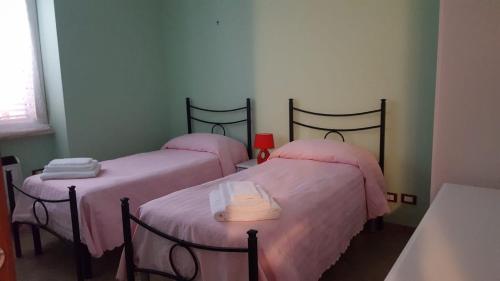 Habitación con 2 camas y sábanas rosas. en IL PARADISO, en Latina