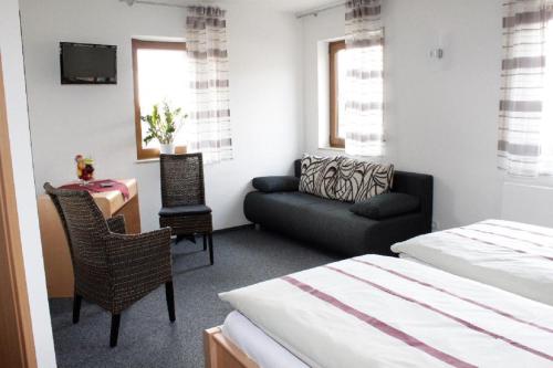 a bedroom with a bed and a couch and a chair at Landgasthaus Badischer Hof in Großrinderfeld