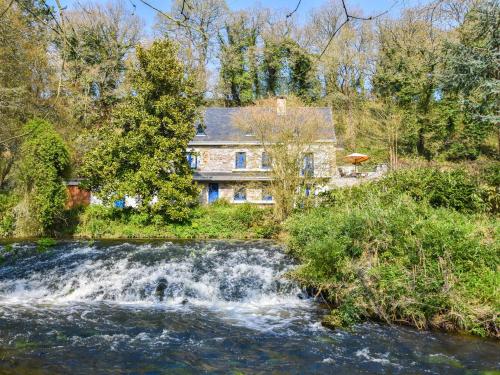 a house next to a river with a waterfall at Superb holiday home with private garden in Yvias