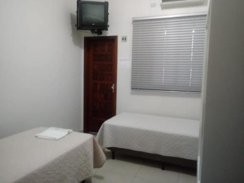 Habitación con 2 camas, TV y ventana. en Hotel Capri, en Nova Santa Medianeira