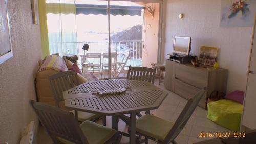 d'un salon avec une table et des chaises ainsi que d'un balcon. dans l'établissement Face à la mer Résidence Les Elmes, à Banyuls-sur-Mer