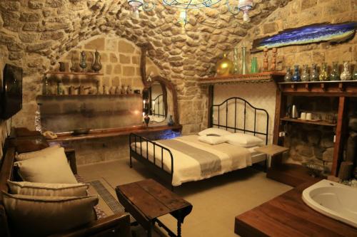 ein Schlafzimmer mit einem Bett in einem Zimmer mit Steinwänden in der Unterkunft Ashash House in Akkon