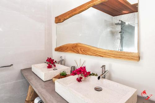 two sinks in a bathroom with a mirror and flowers at Villa Fleur d'O in Le Robert