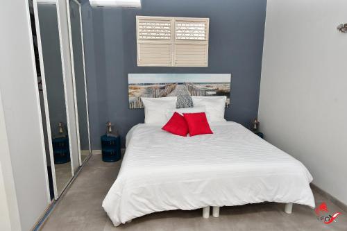 a bedroom with a white bed with two red pillows at Villa Fleur d'O in Le Robert