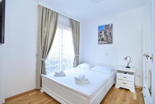 a white bedroom with a bed and a window at Apartment Bojana in Budva