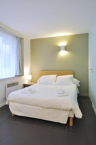 a bedroom with a large white bed with a window at Temporesidence Chateauneuf in Bayonne