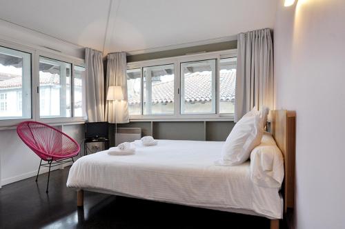 a bedroom with a white bed and a red chair at Temporesidence Chateauneuf in Bayonne