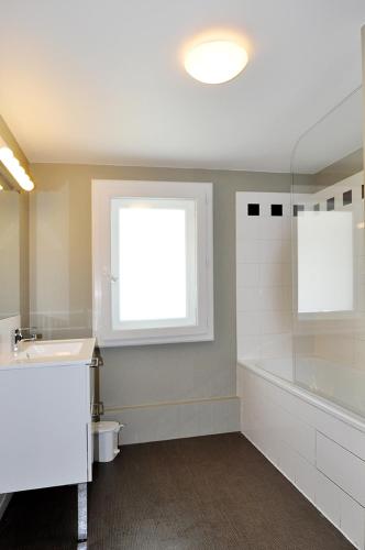 a bathroom with a sink and a tub and a window at Temporesidence Chateauneuf in Bayonne