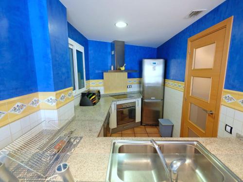 cocina con paredes azules y fregadero de acero inoxidable en Apartment Playasol 1 by Interhome, en Les Cases d'Alcanar