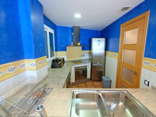 a kitchen with blue walls and a stainless steel sink at Apartment Playasol 1 by Interhome in Les Cases d'Alcanar