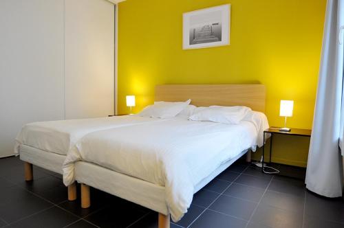 a bedroom with a large bed with a yellow wall at Temporesidence Chateauneuf in Bayonne