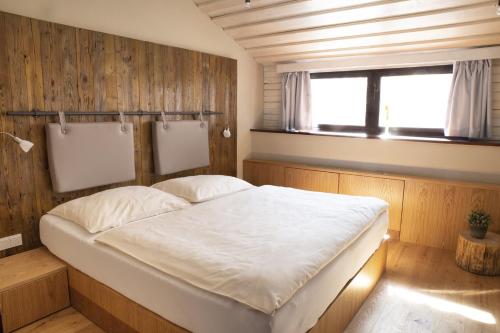 a bed in a room with a wooden wall at Koliba u Cerneho Medveda in Zlín