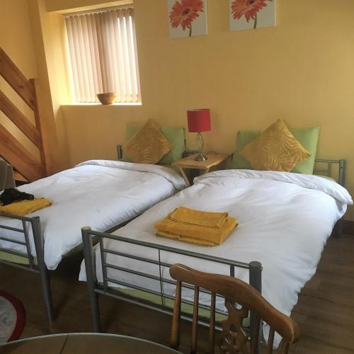 a room with two beds and a table with a lamp at Heddfan in Carmarthen