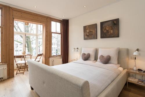 Un dormitorio con una gran cama blanca y una mesa en A B&B Amsterdam, en Ámsterdam