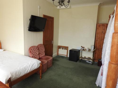 a bedroom with a bed and a tv and a chair at Môr Wyn Guest House in Barmouth