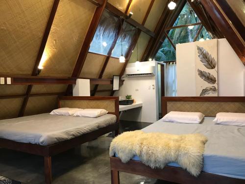 two beds in a room with windows at Dahun Villas Siargao in General Luna