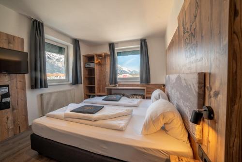 a bedroom with two beds and a tv and windows at BinderS Budget City-Mountain Hotel in Innsbruck