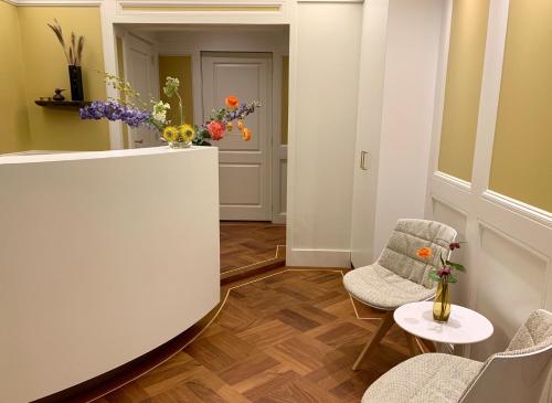 um corredor com duas cadeiras, uma mesa e flores em Hotel Imperial em Amsterdã