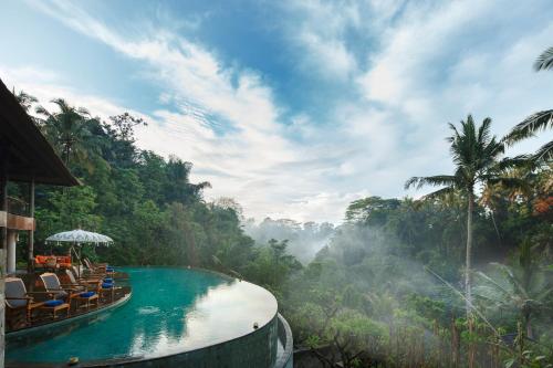 a pool in the middle of a jungle with chairs and trees at Natya Resort Ubud in Ubud