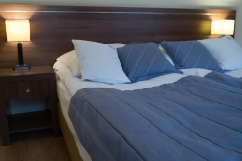 a bed with blue sheets and pillows next to a lamp at Aparthotel Bellamonte in Zakopane