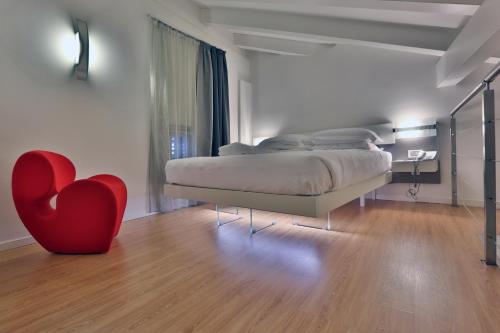 ein Schlafzimmer mit einem Bett und einem roten Herzstuhl in der Unterkunft Urban Hotel Design in Triest