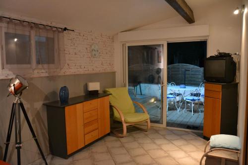 a living room with a television and a table with chairs at Gite L'Acacia in Lagorce