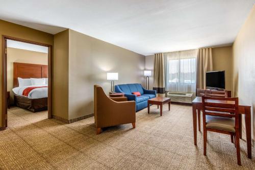 a hotel room with a bed and a blue couch at Comfort Inn & Suites in McComb