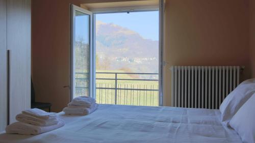 a bedroom with a large window with towels on a bed at Italianway - Casasco 79 in San Fedele Intelvi