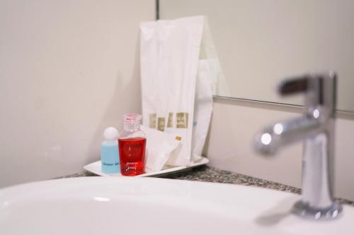 a bathroom sink with a bottle of soap and a mirror at White House Bizotel in Bangkok