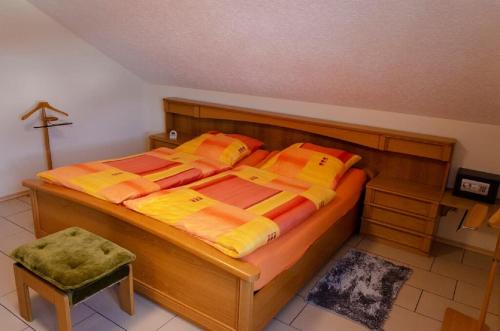a bedroom with a wooden bed with orange and yellow pillows at Ferienwohnung Zebrowski in Zandt
