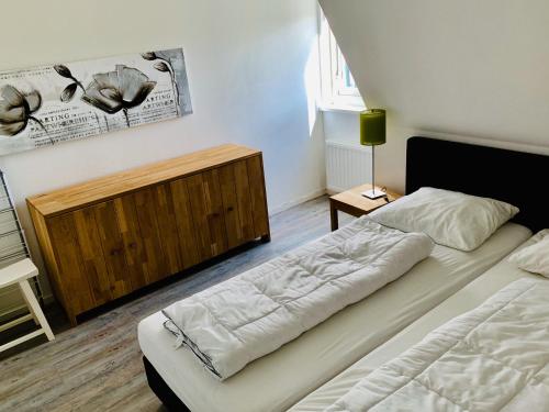 een slaapkamer met 2 bedden en een houten kast bij De Eerste Stuiver in Hollum