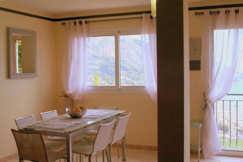 une table à manger avec des chaises blanches et une fenêtre dans l'établissement Les Citronniers d'Azur, à Menton