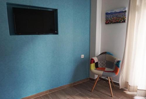 een kamer met een blauwe muur met een stoel en een televisie bij Marlera Corfu Old Town Apt in Corfu-stad