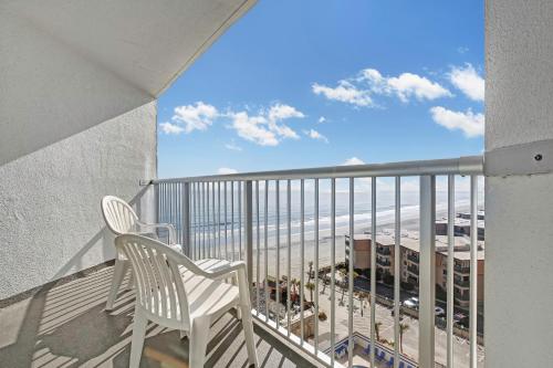 a balcony with a chair and a view of the beach at Ocean Annie's Resorts in Myrtle Beach