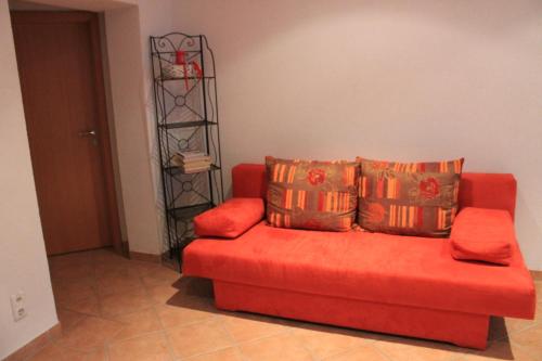 1 sofá rojo con 3 almohadas en la sala de estar en Ferienwohnung Zu den Weinbergen, en Traustadt