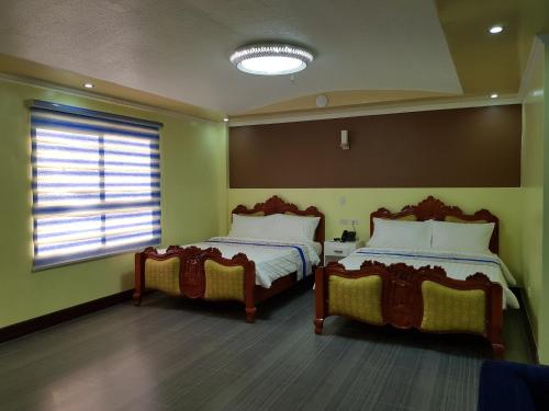 two beds in a room with green walls and a window at Santiago Cove Hotel and Restaurant in Santiago