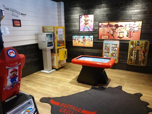 een kamer met een videospelletjesmachine en een rode bank bij Ekho Hotel Grenoble Nord Saint Egrève in Saint-Égrève