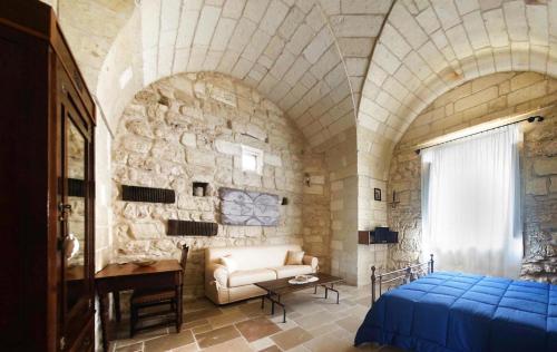 - une chambre avec un lit et un mur en pierre dans l'établissement Masseria Asteri B&B, à Cannole