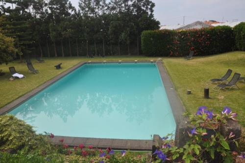 a large swimming pool in a yard with flowers at Convento de São Francisco in Vila Franca do Campo