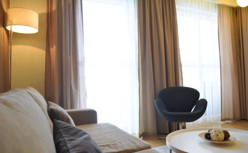 a living room with a couch and a chair in front of a window at IRS ROYAL APARTMENTS Apartamenty IRS Fregata in Gdańsk