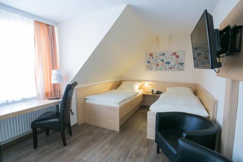 um quarto com 2 camas, uma secretária e uma cadeira em Bürgermeisterkapelle em Hildesheim