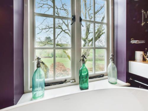 three bottles sitting on a sink in front of a window at Westerleigh Cottage in Cheltenham